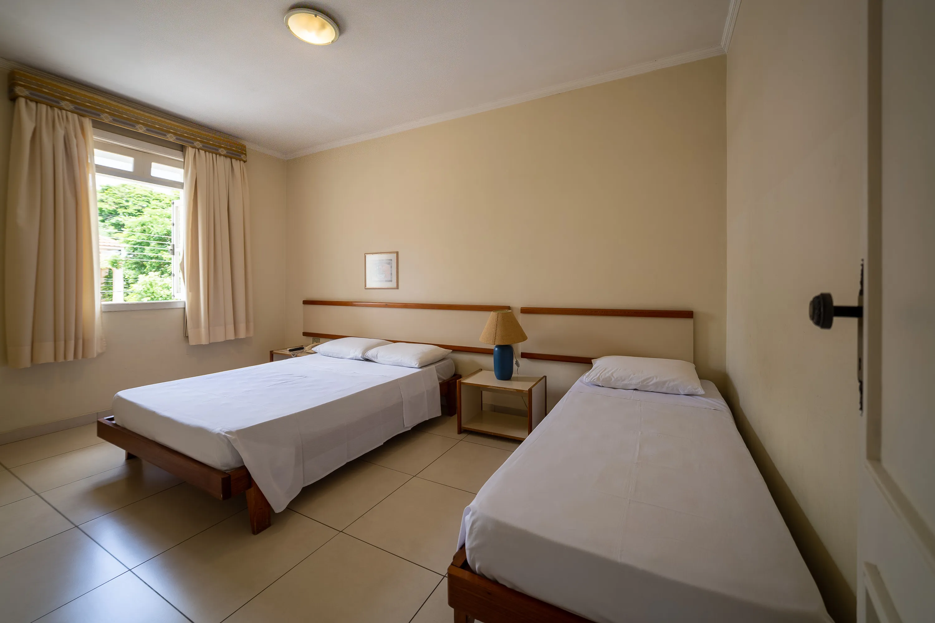 foto de quarto amplo com ar condicionado, bem arejado e iluminado, com uma cama de casal e uma cama de solteiro